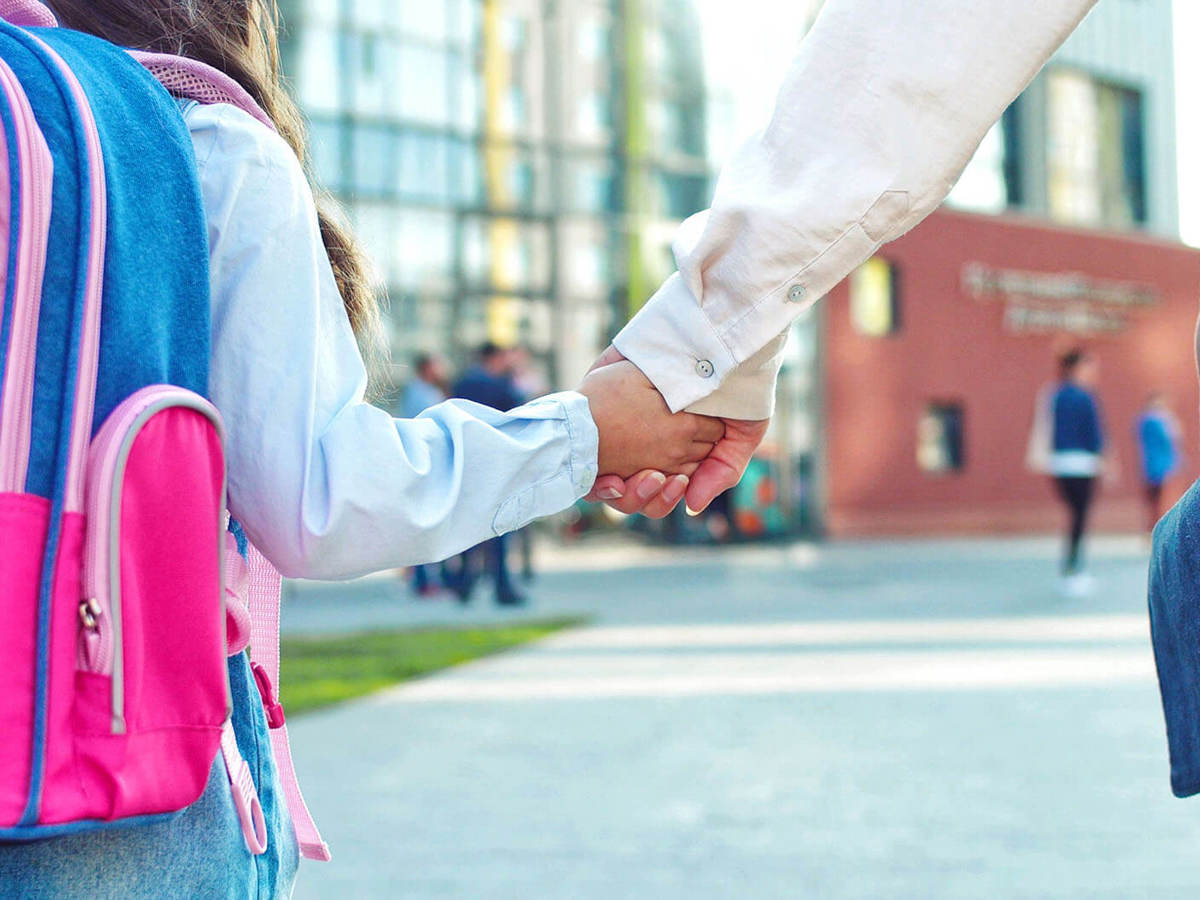 school-environment pupil and their guardian holding hands walking towards a school