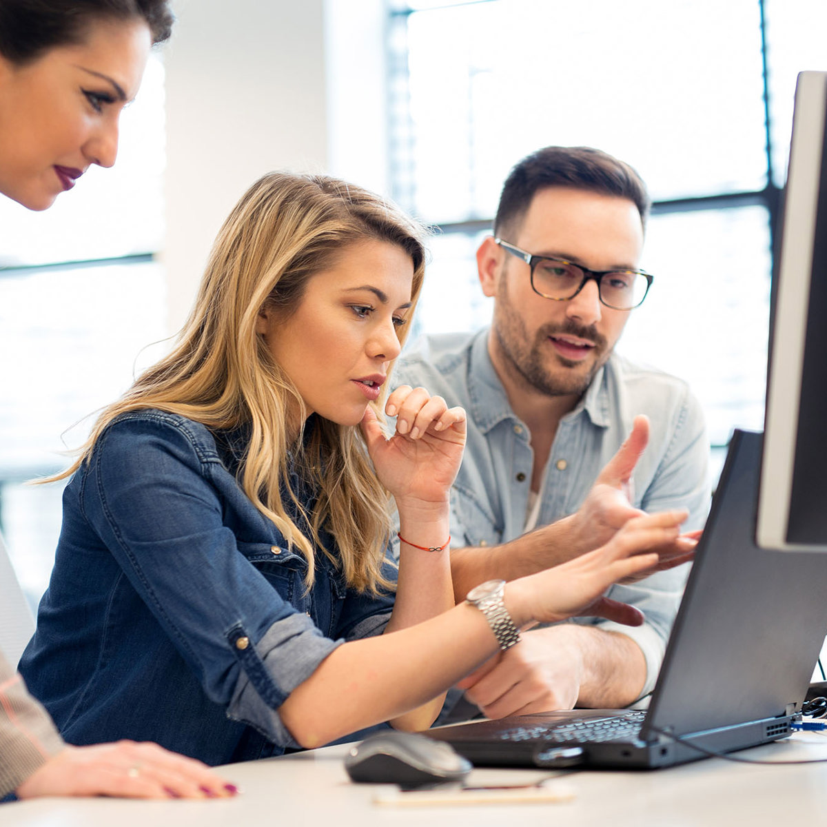 training three people overlooking one laptop in discussion