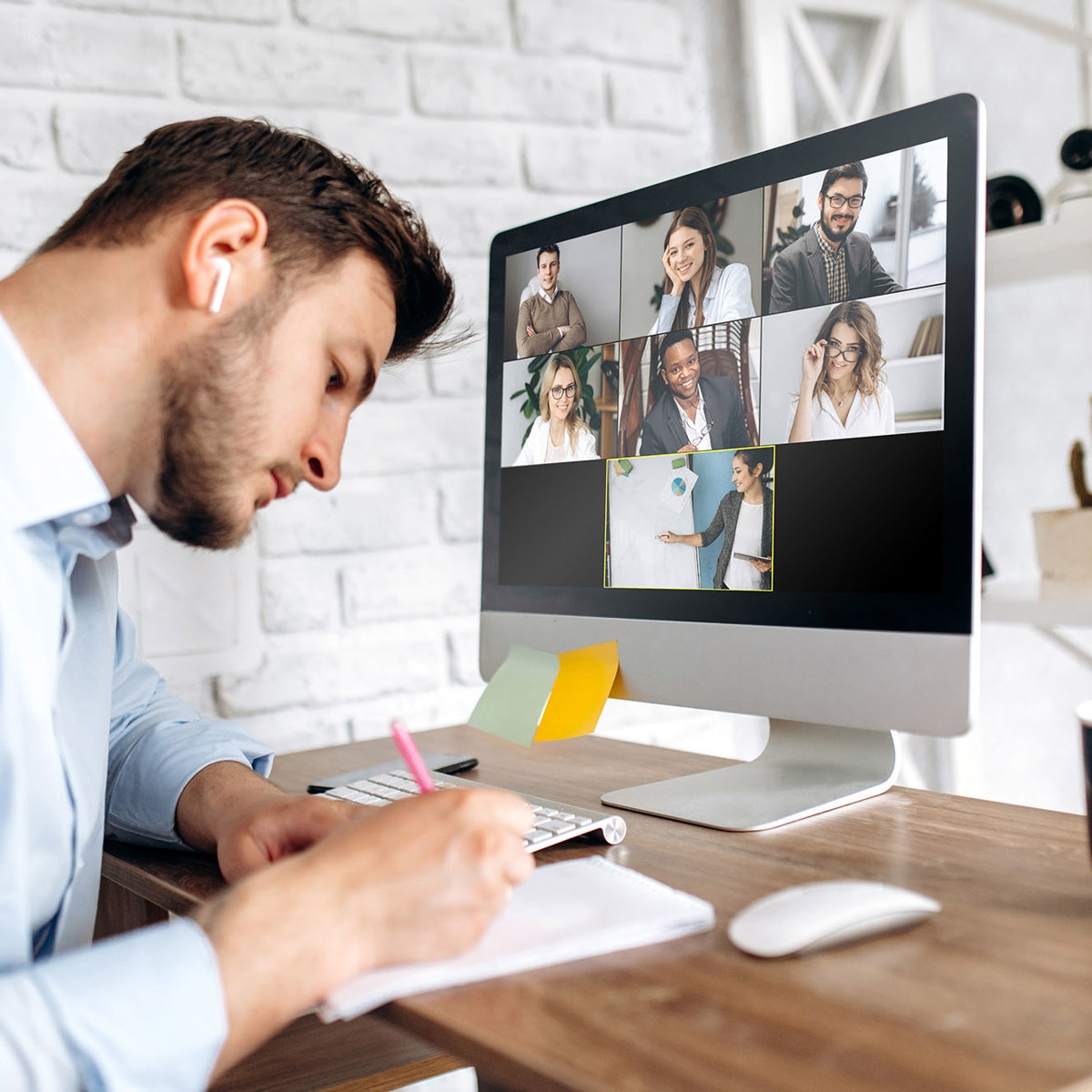 training man writing notes whilst on a video call with 7 others