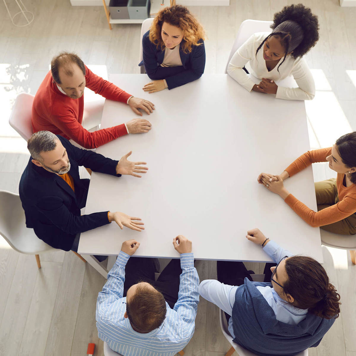 seven people in a meeting talking around a table