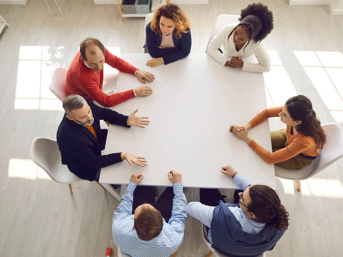 seven people in a meeting talking around a table