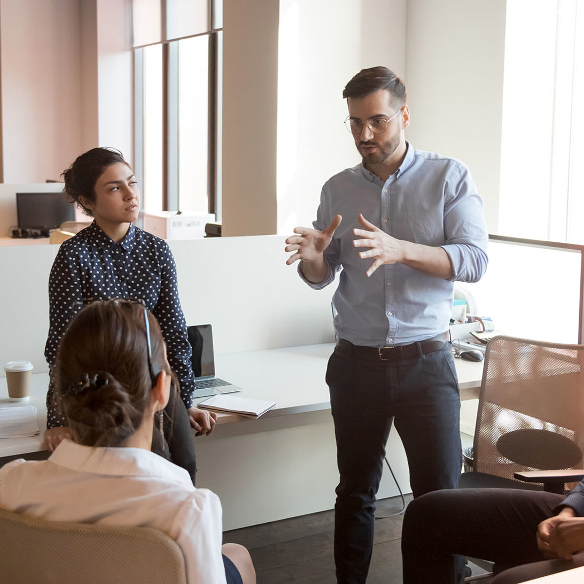 training man standing talking to 4 sitting others 