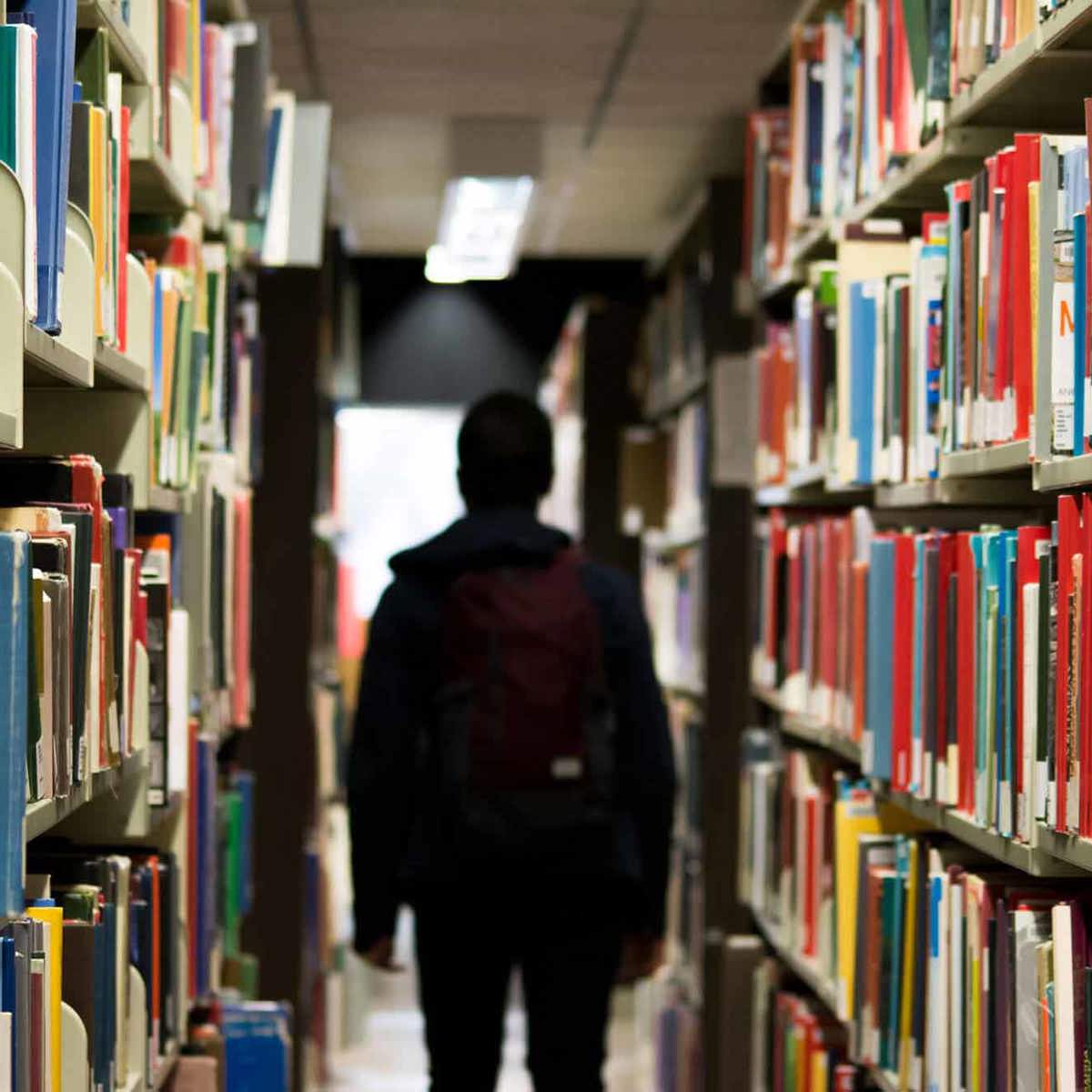 school-environment someone walking past filled book shelves 