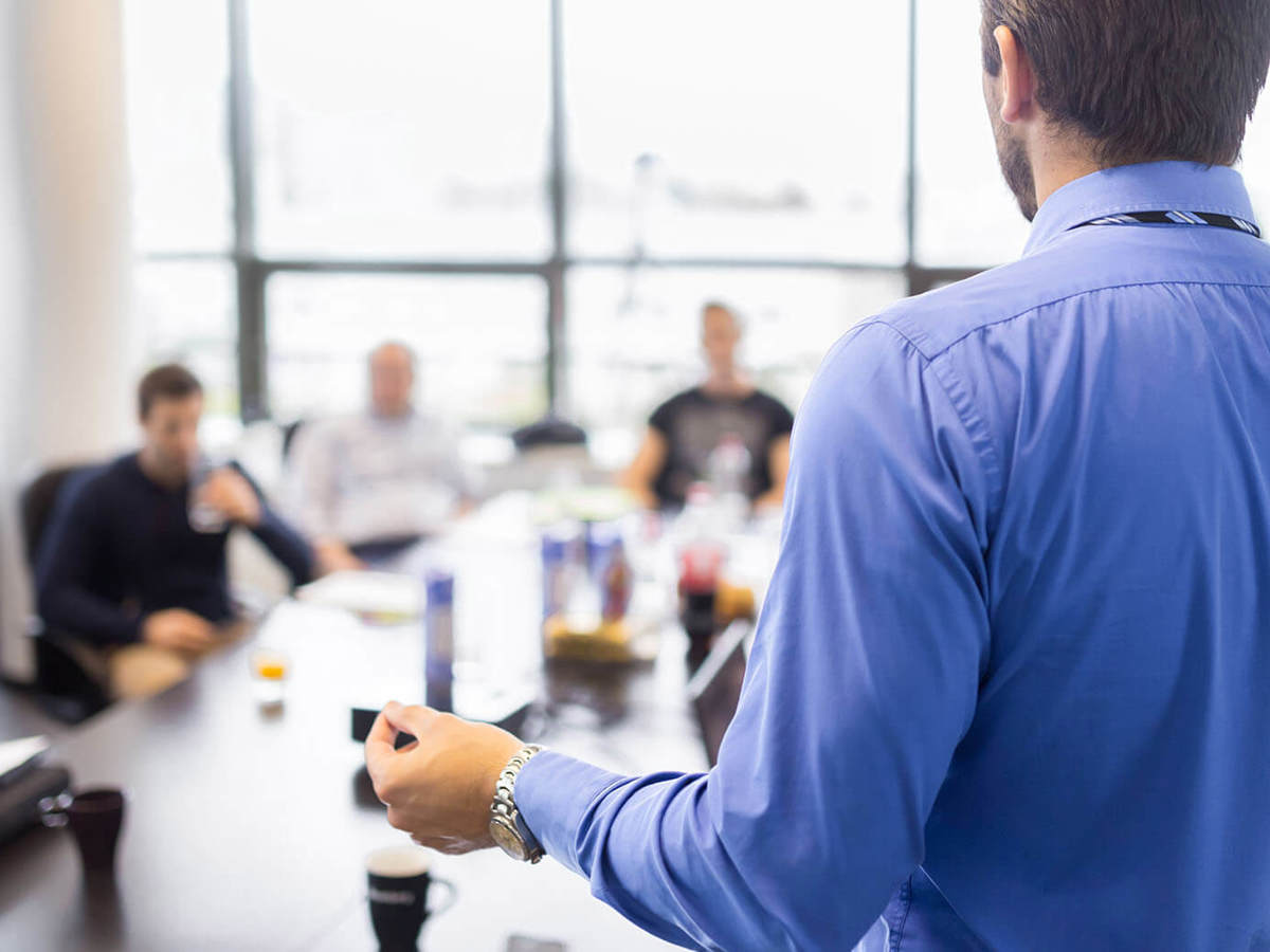 training man presenting to small blurred group